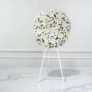 Corona fúnebre blanca con lirios y flor argentina frescas en caballete