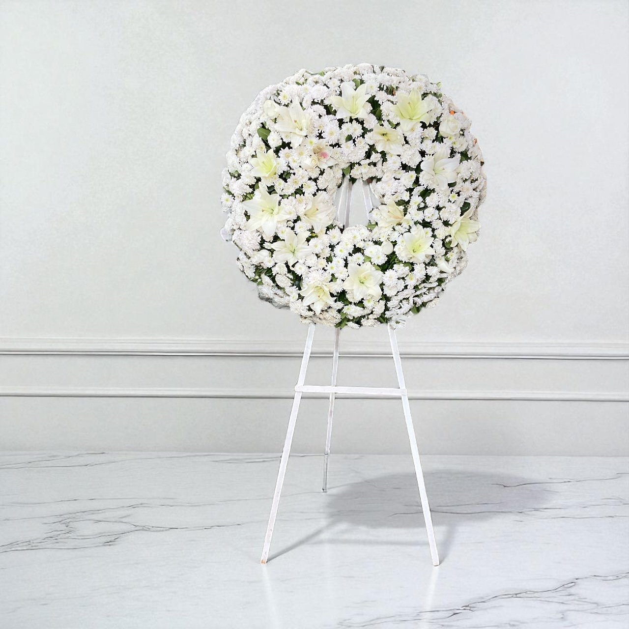 Corona fúnebre blanca con lirios y flor argentina frescas en caballete