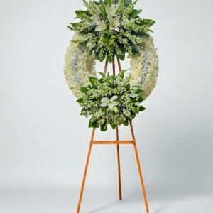 Corona fúnebre premium de doble medallon con rosas blancas, lirios y follaje natural sobre tripie de madera.