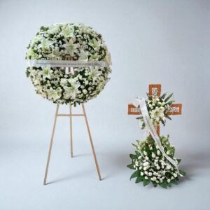 Corona fúnebre blanca y cruz floral, ideal para homenajes familiares.