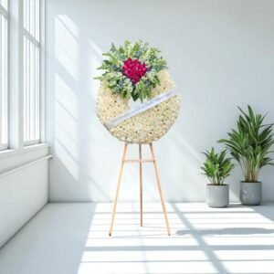 Corona fúnebre elegante con rosas blancas y rosas fucsia sobre caballete de madera, ideal para expresar condolencias con distinción.